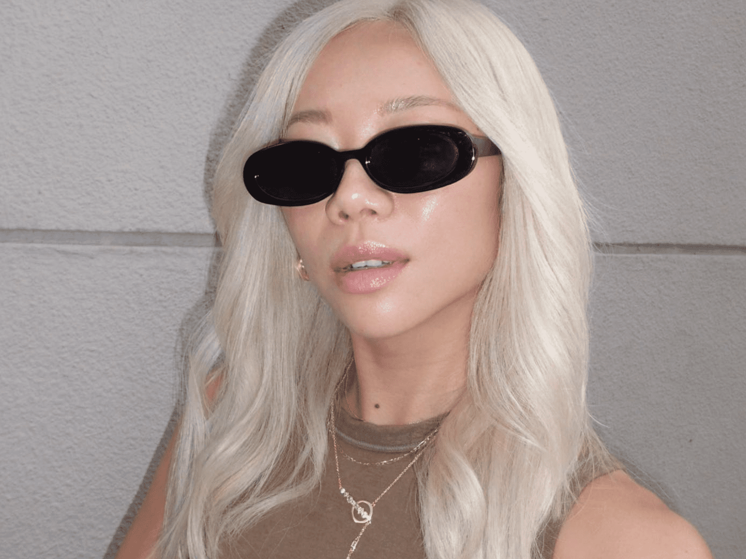 Byrdie's former editorial director Faith Xue wearing black round sunglasses with her bright platinum blonde hair.