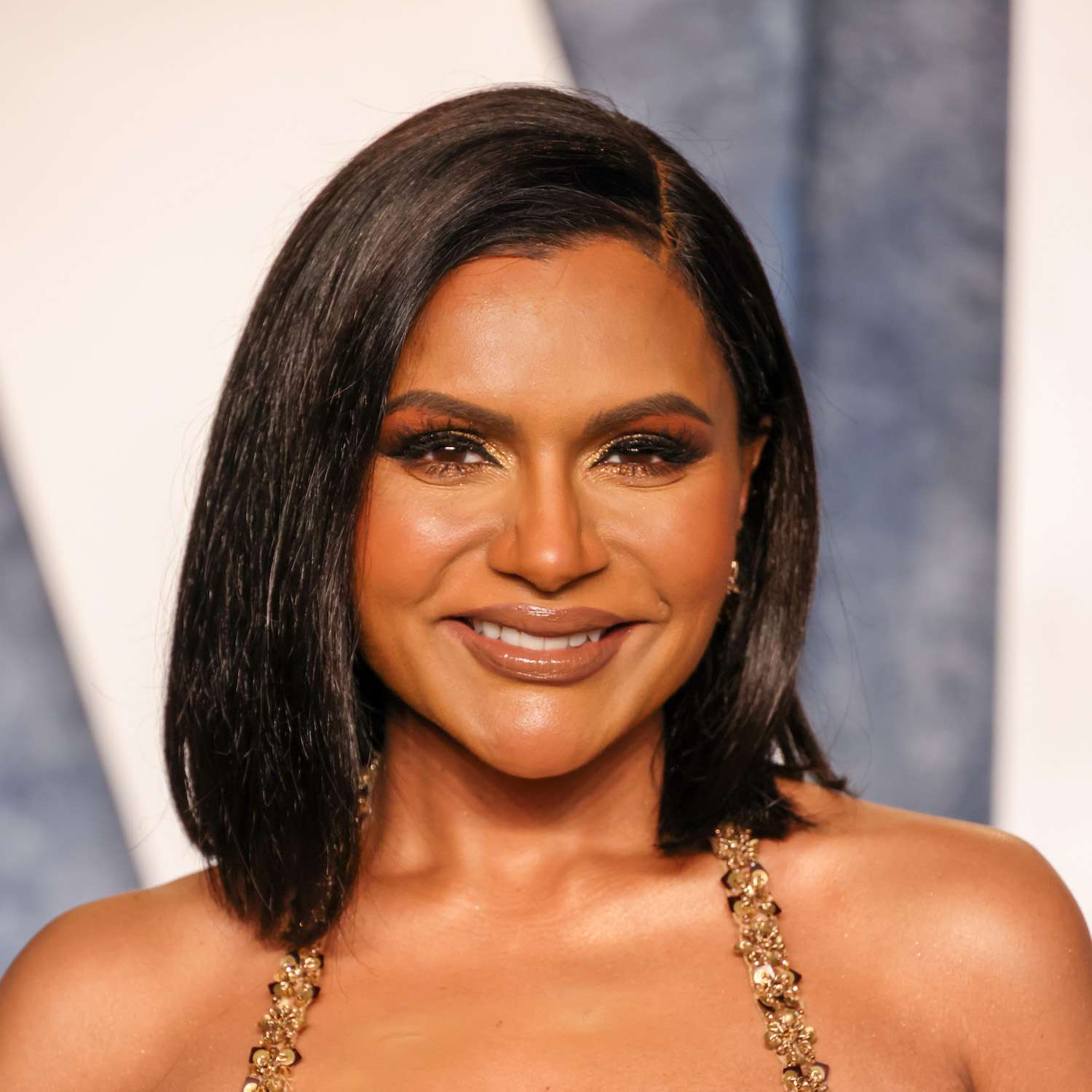 Mindy Kaling wears a sleek, face-framing bob hairstyle with side part
