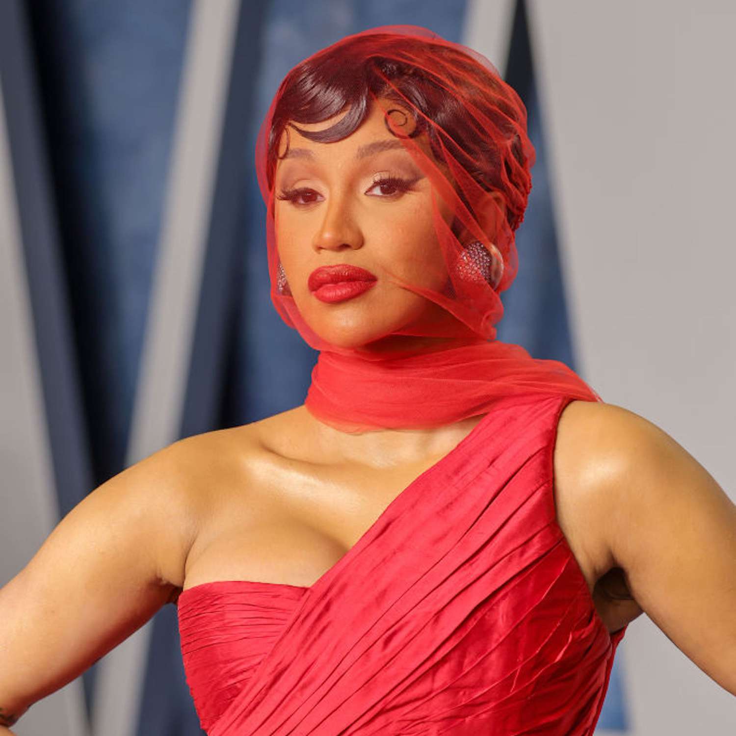 Cardi B with pin curls and a red scarf over her face