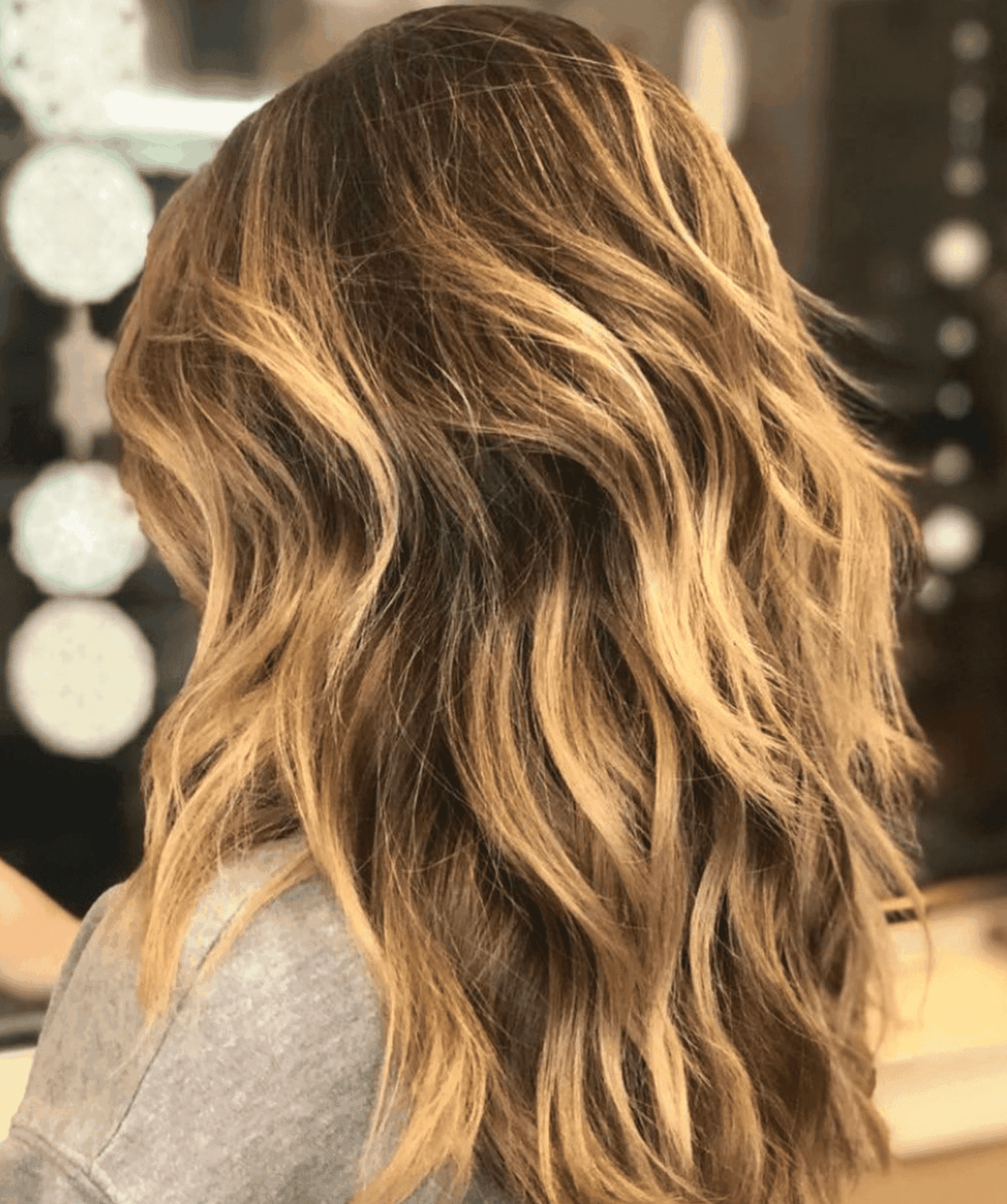 Warm teasylights on layered, mid-length hair, viewed from the back