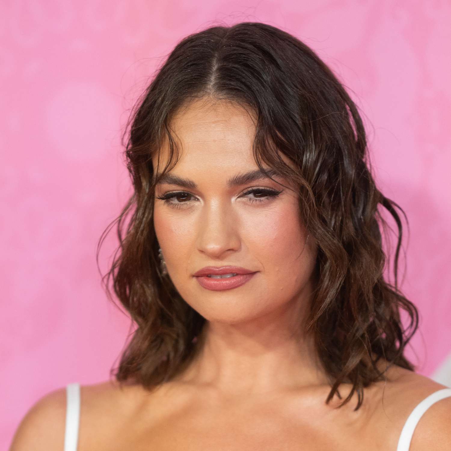 Lily James wears a long bob hairstyle with romantic curls