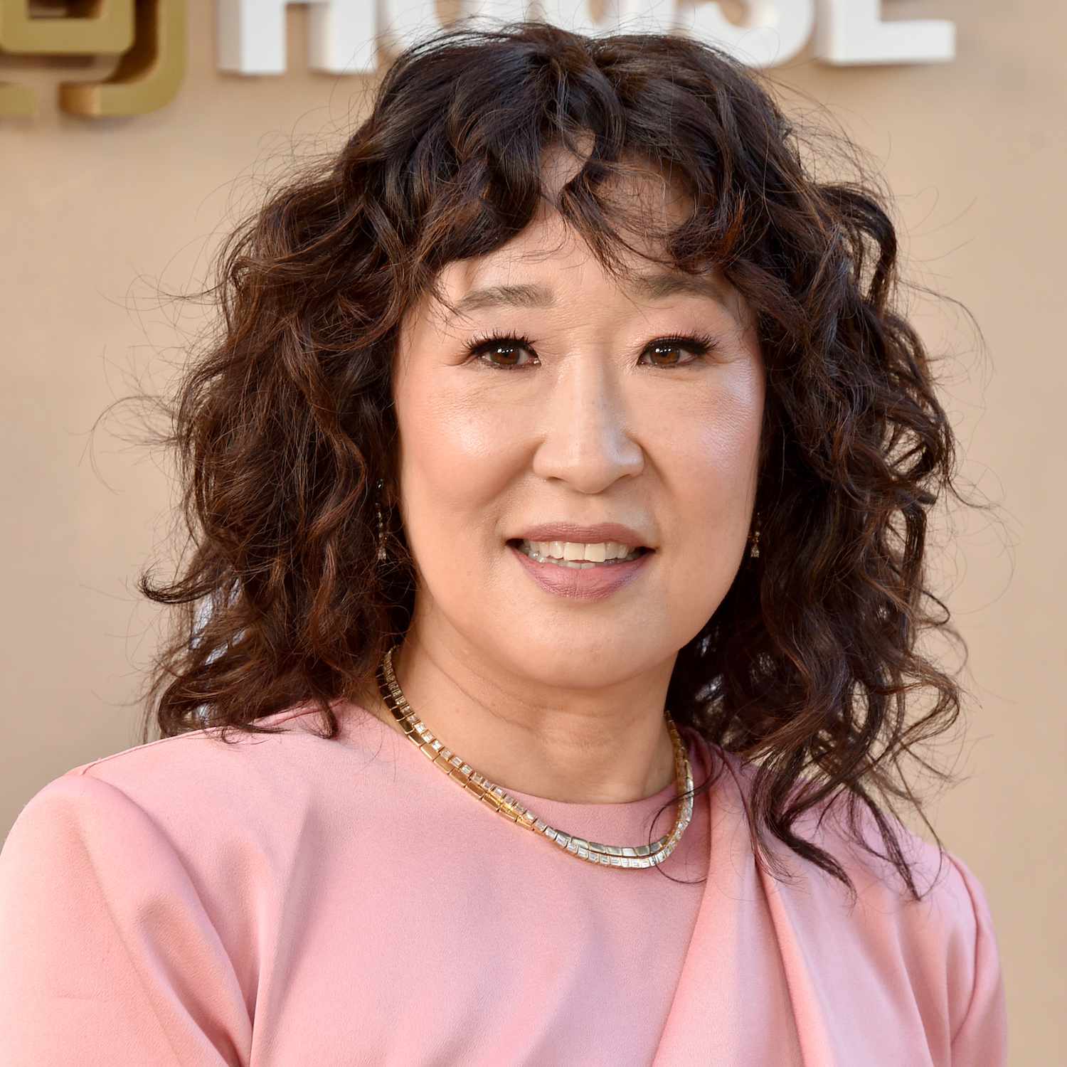 Sandra Oh wears a wavy shag hairstyle with bangs and face-framing layers