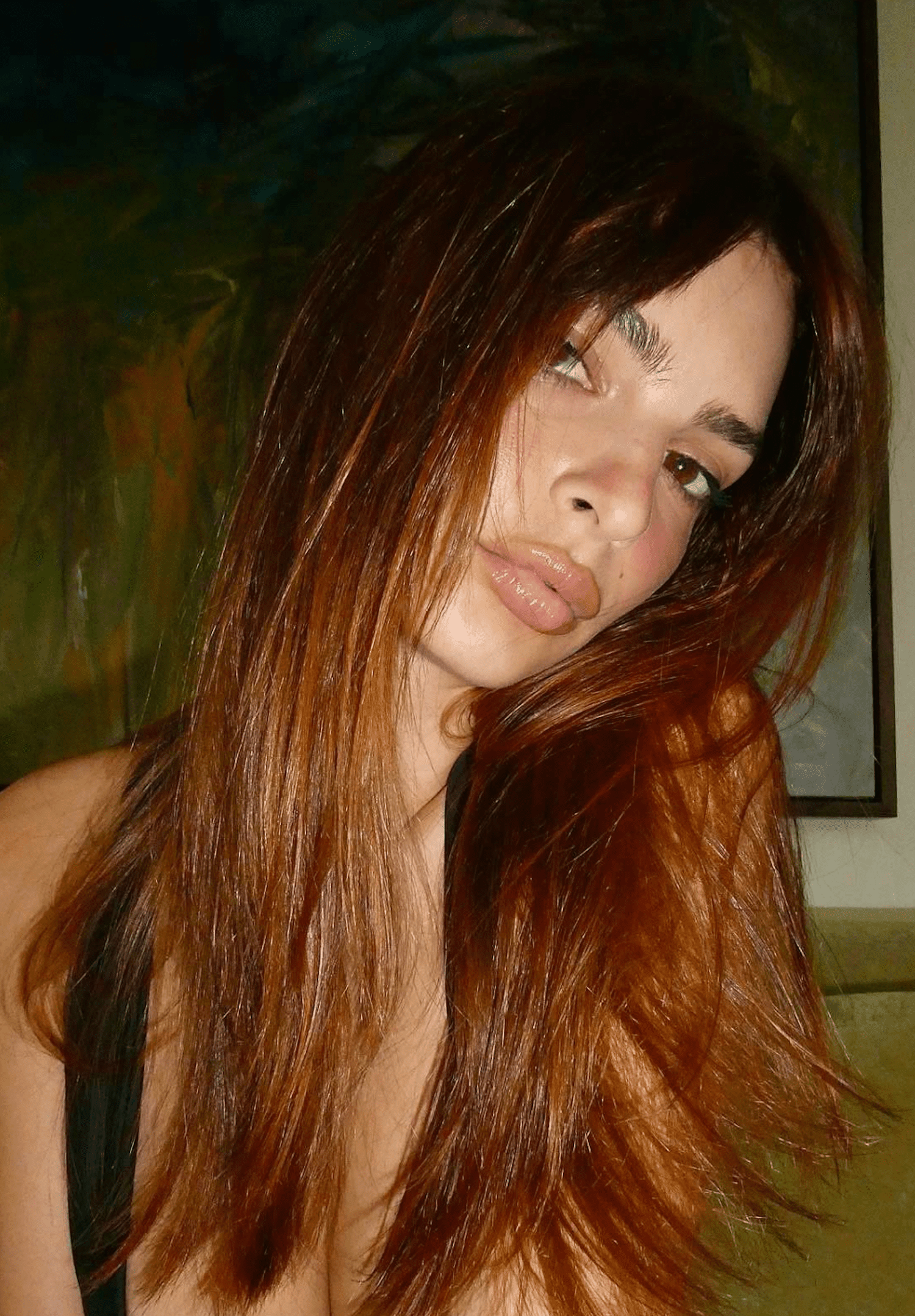 EMRATA SITS ON A COUCH AND TAKES A SELFIE OF HER NEW COPPER RED HAIR COLOR