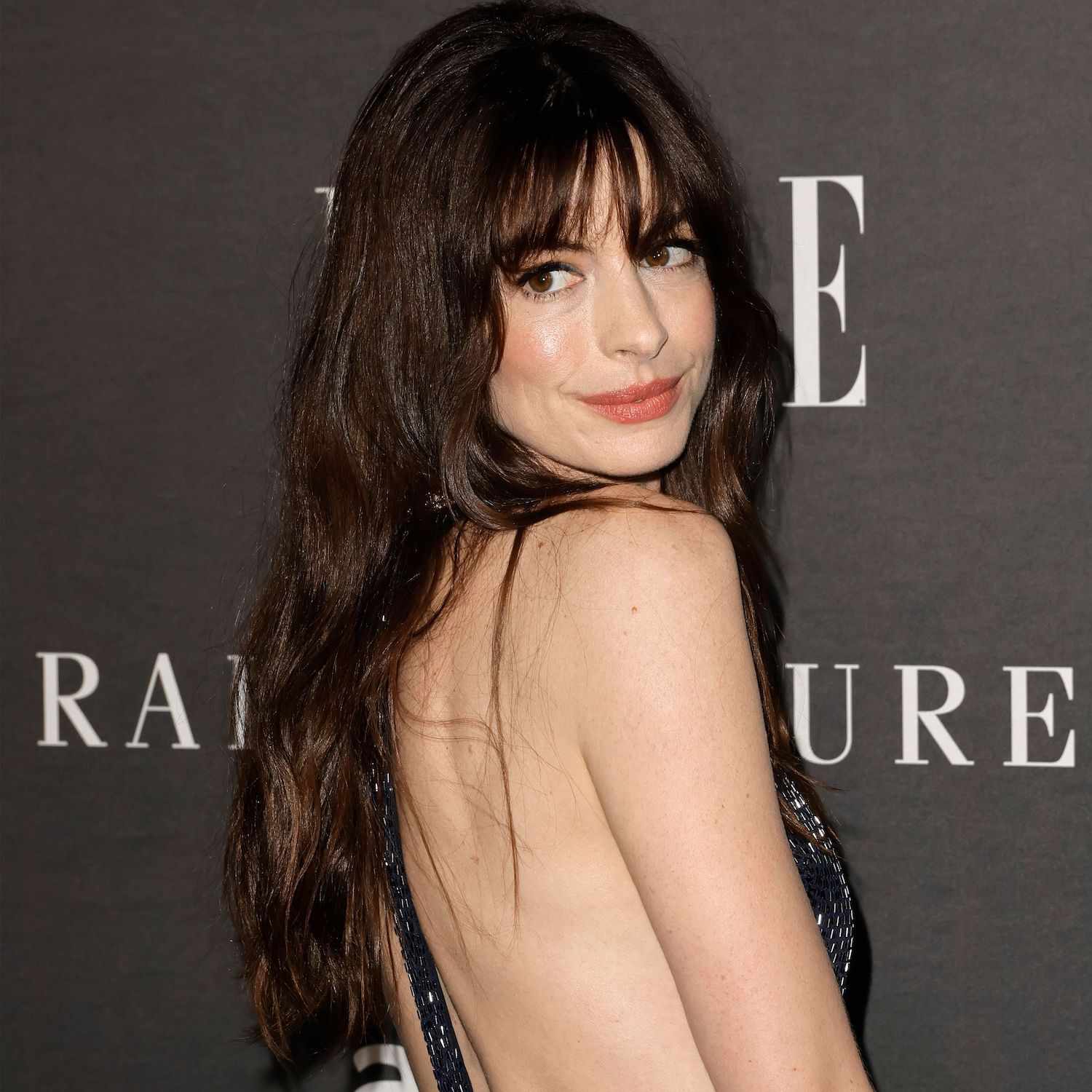 Anne Hathaway wears a long, wavy hairstyle with wispy bangs