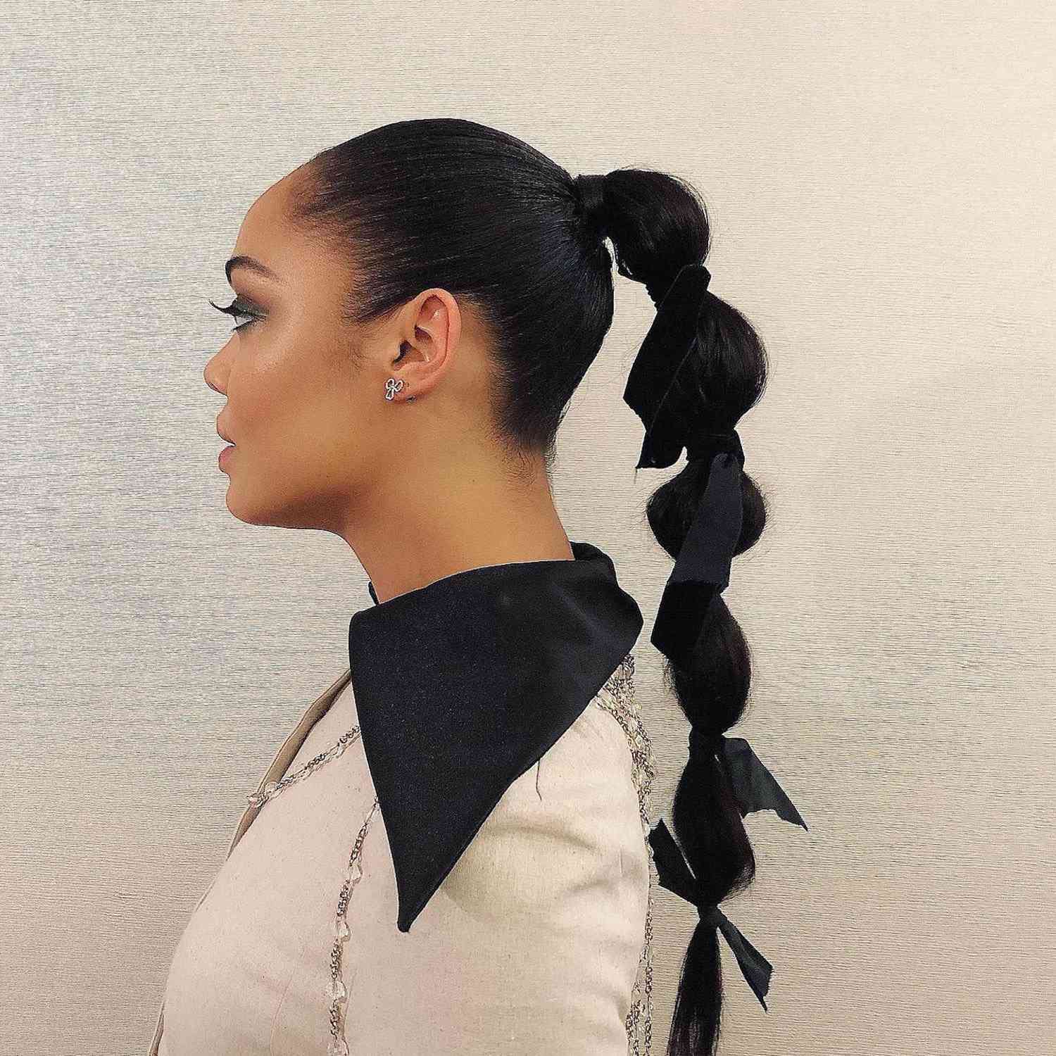 Tessa Thompson in profile, her hair in a bubble ponytail with bows