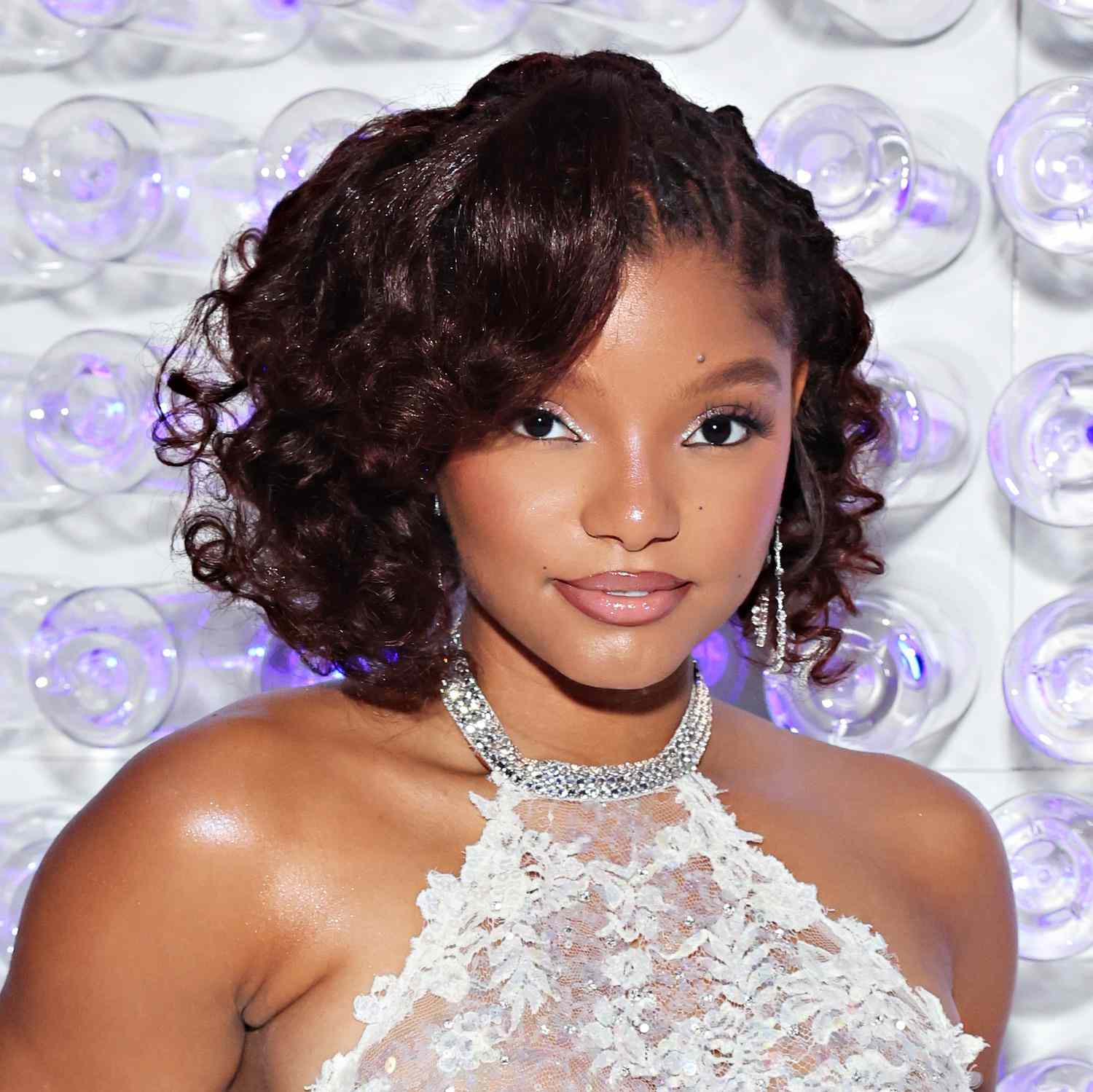 Halle Bailey wears a curly bob-length hairstyle with locs at roots and face-framing layers