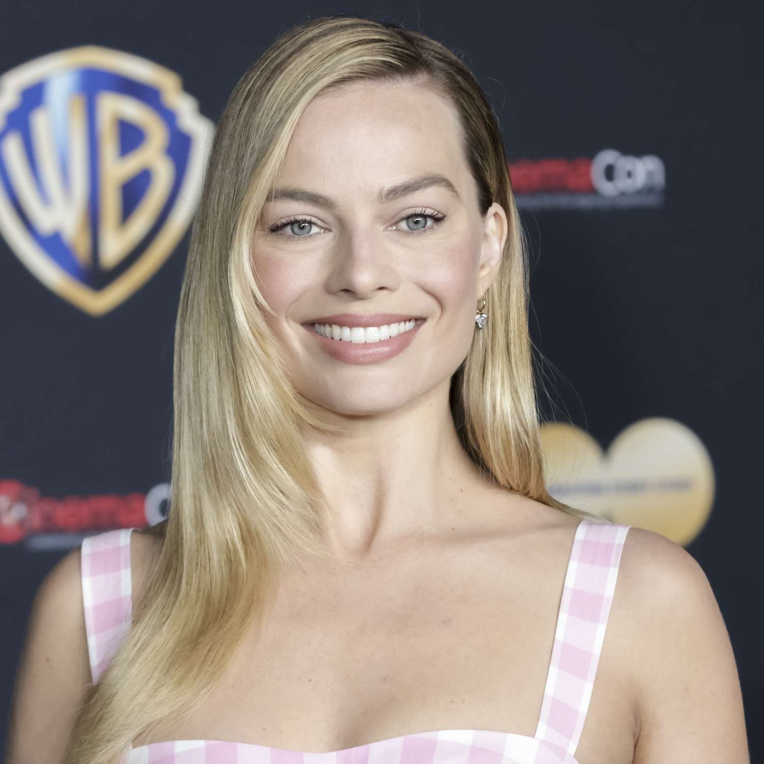 Margot Robbie wears a pink gingham top and sleek hairstyle with side part and face-framing layers