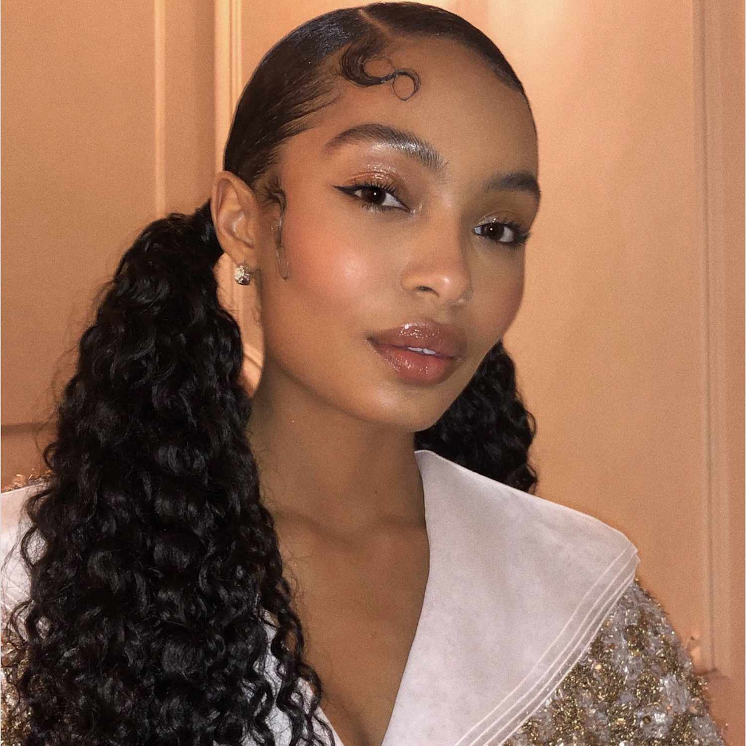 Yara Shahidi wears a curly low pigtail hairstyle with styled edges