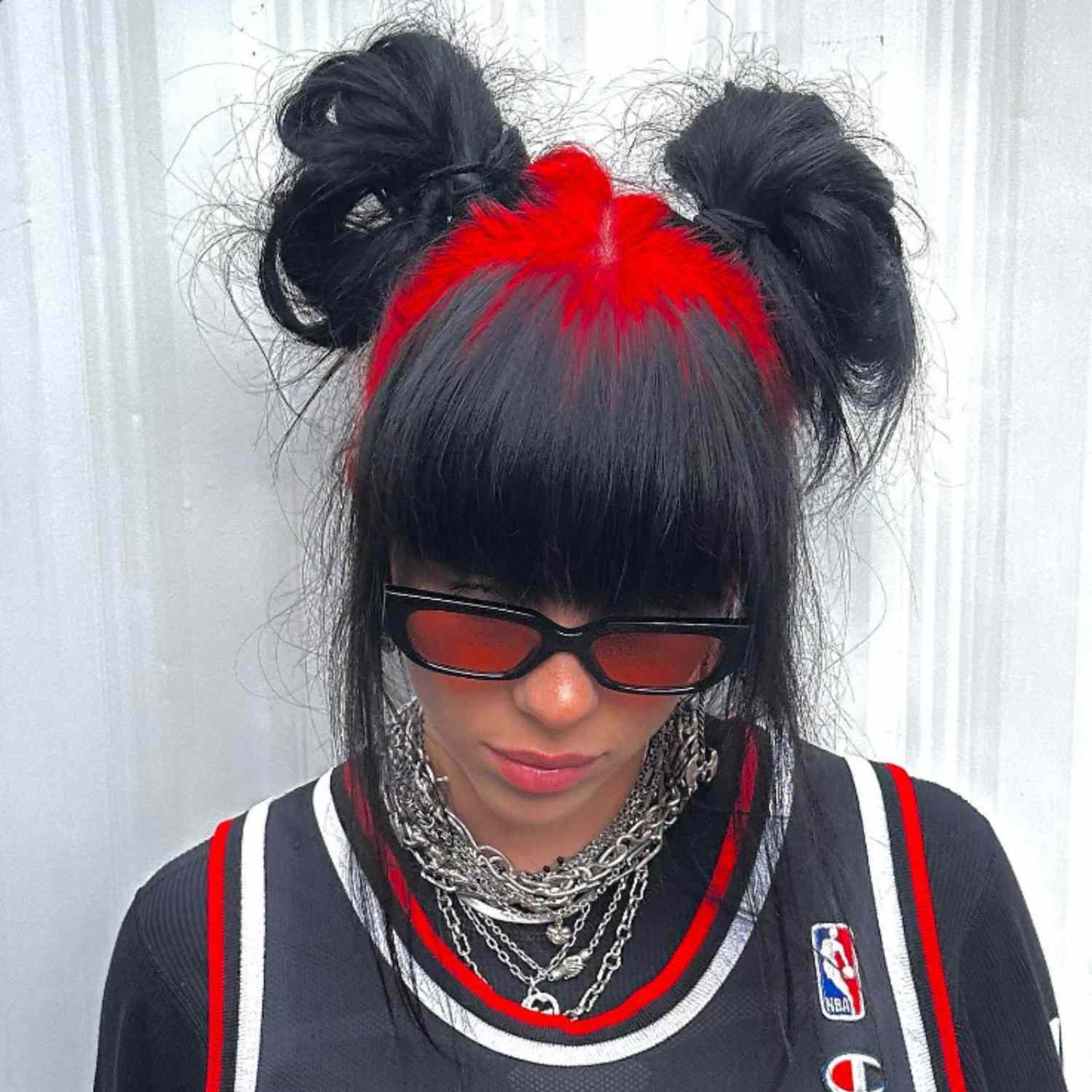 Billie Eilish wearing two space-bun pigtails with black and red hair.