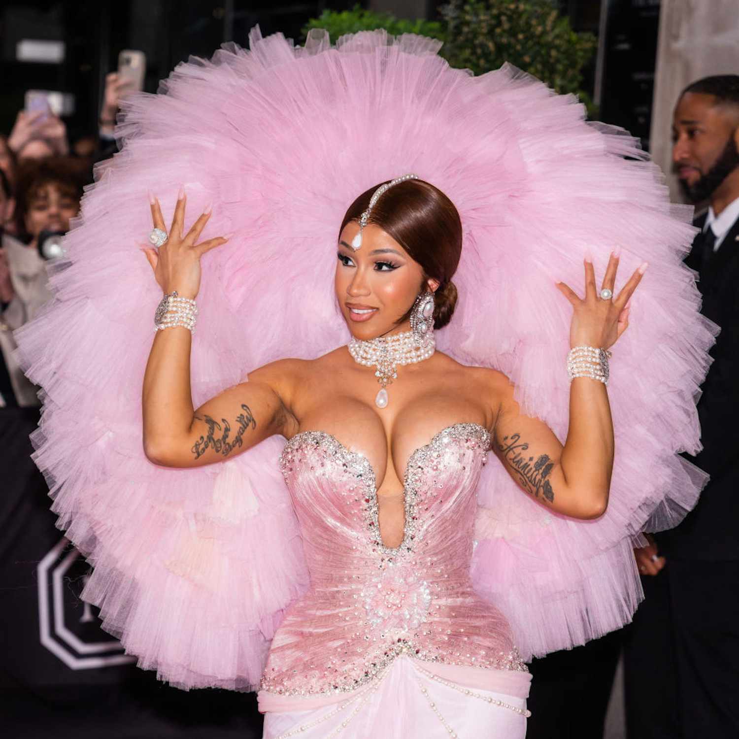 Cardi B with a sleek bun hairstyle, jewels down the center of her part