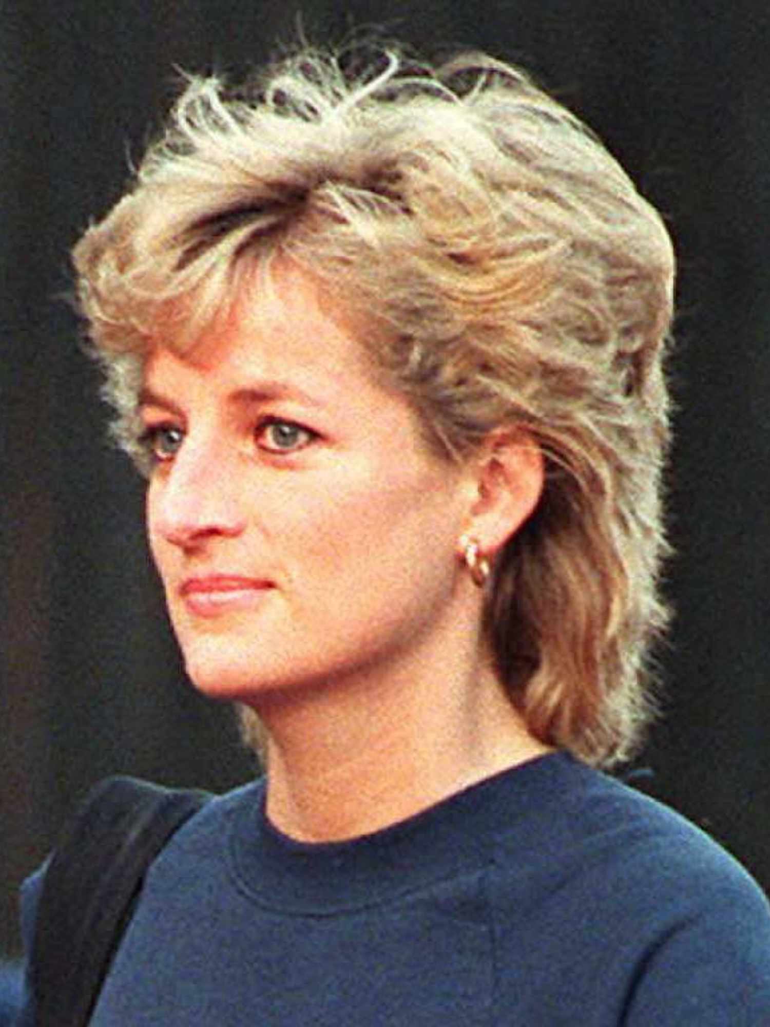 Princess Diana wears a shaggy, layered pixie haircut, gold hoop earrings, and a navy sweatshirt