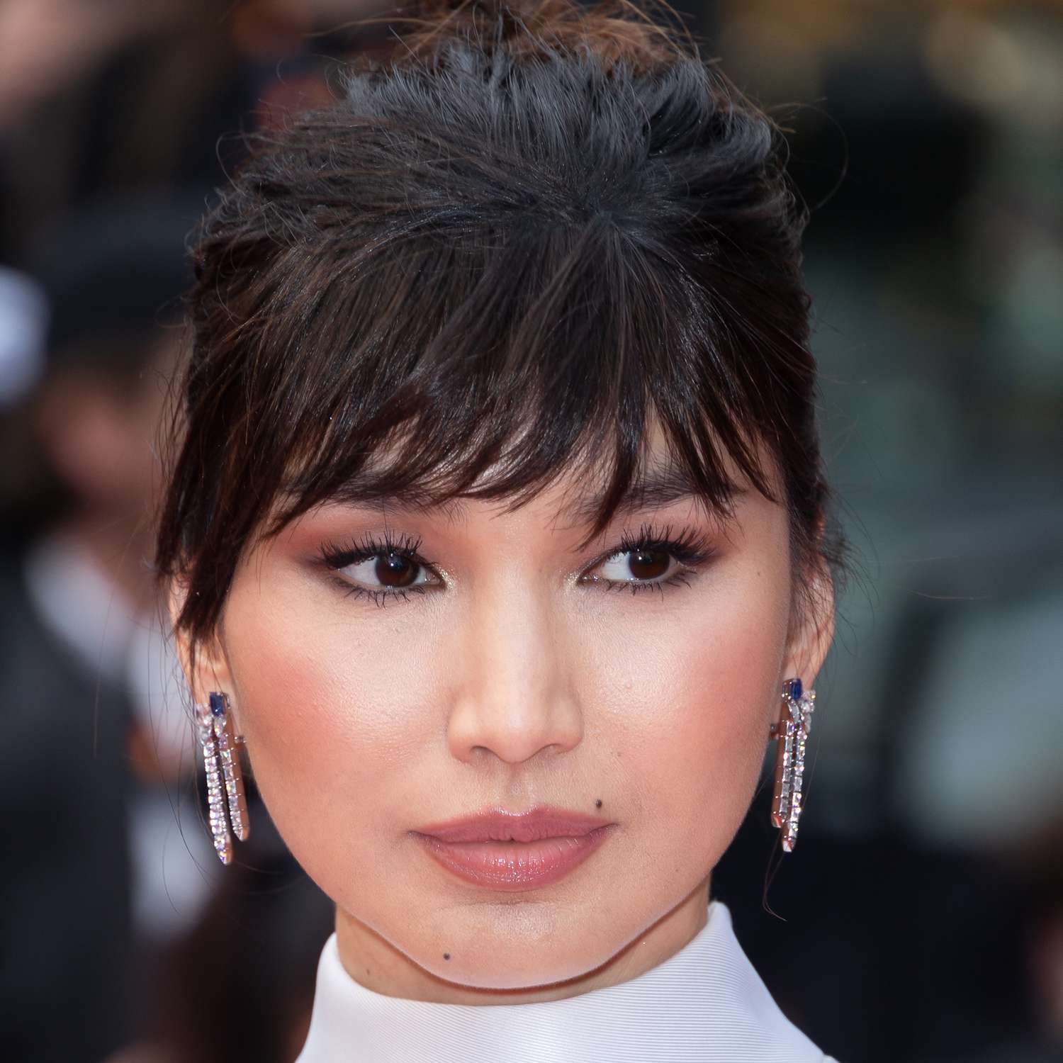 Gemma Chan wears a high collar dress and updo framed with choppy french bangs to Cannes