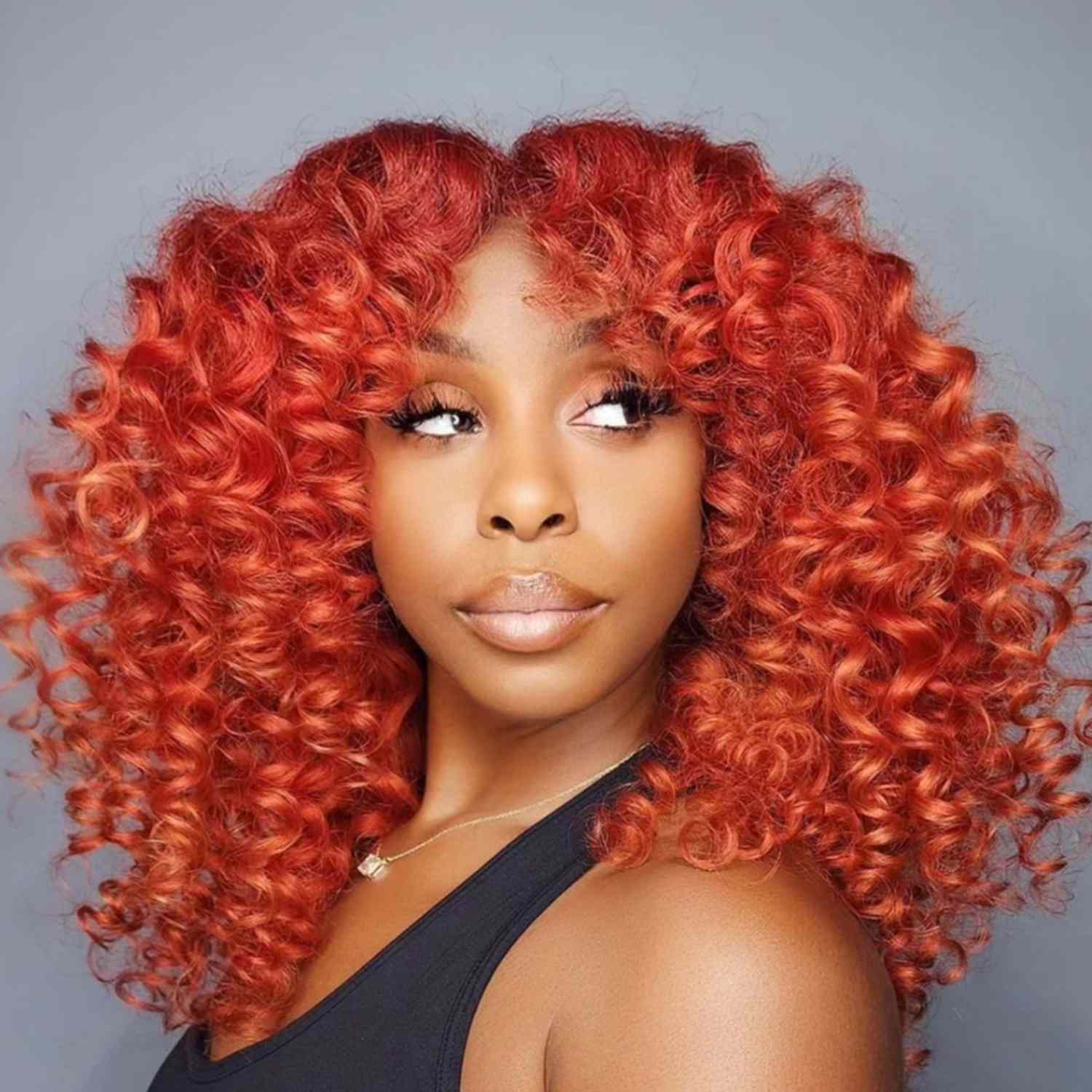 Curly afro hair in a blood orange sangria color.