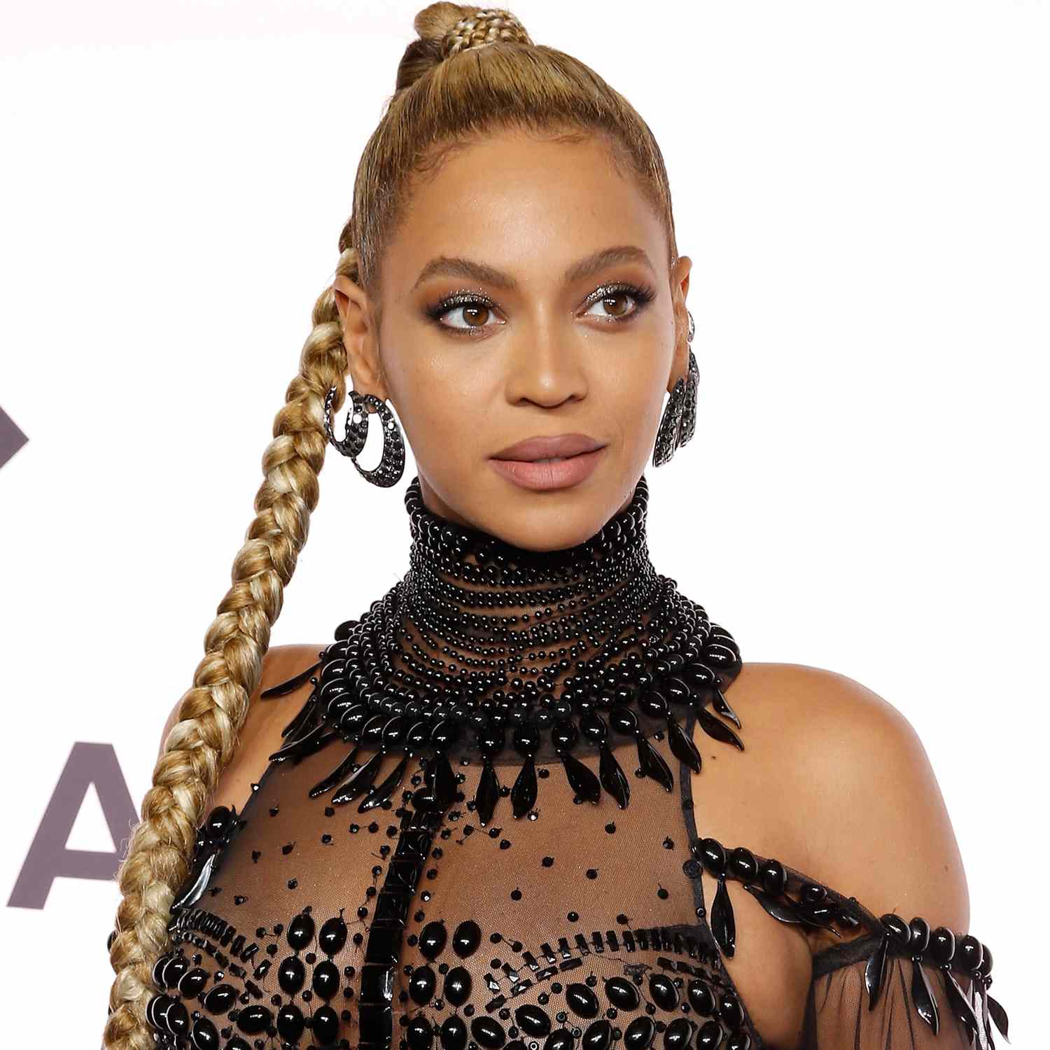 Beyonce wears a single three strand braid with a small braid of hair wrapped around the base. 