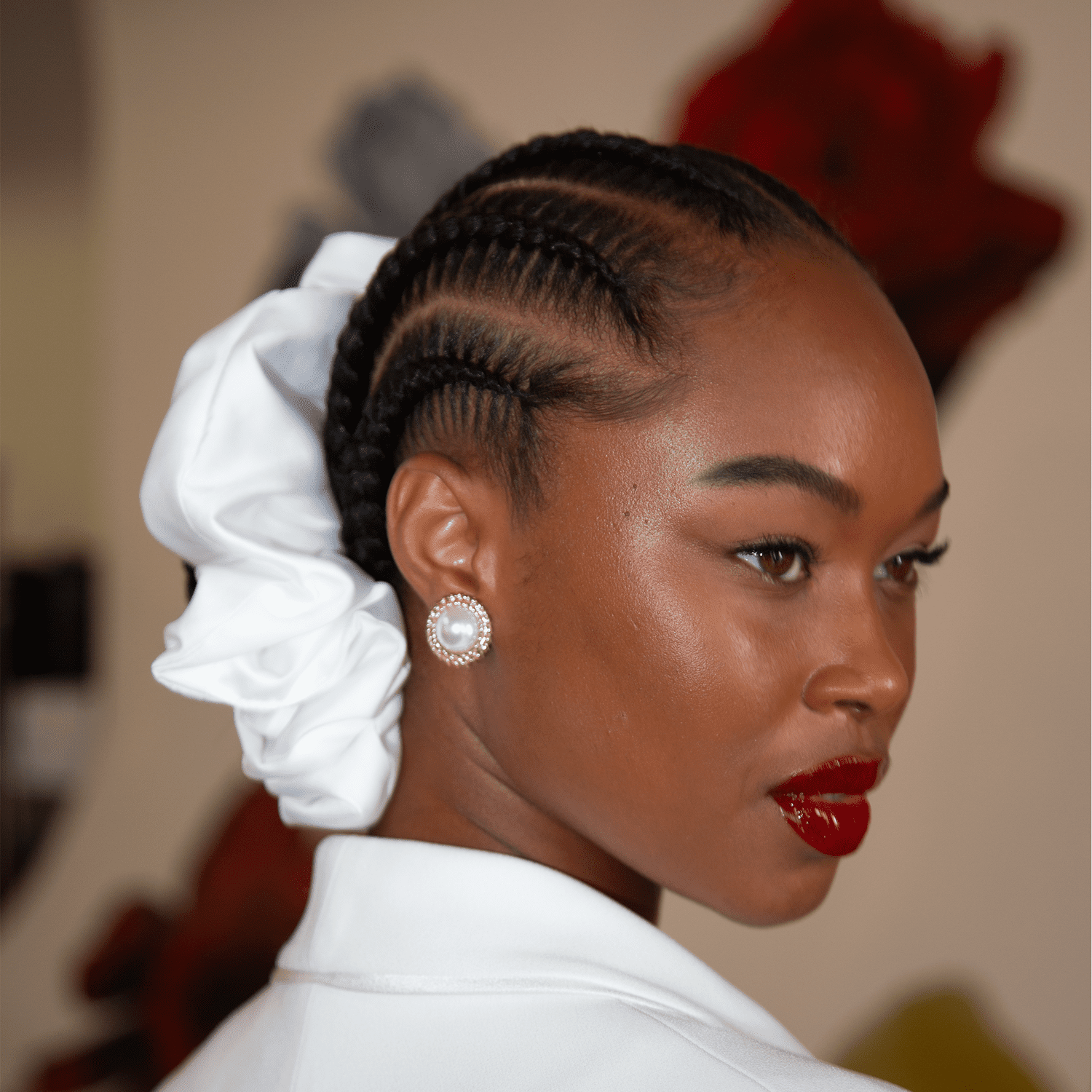 Model with braids leading into a bun with large white scrunchie