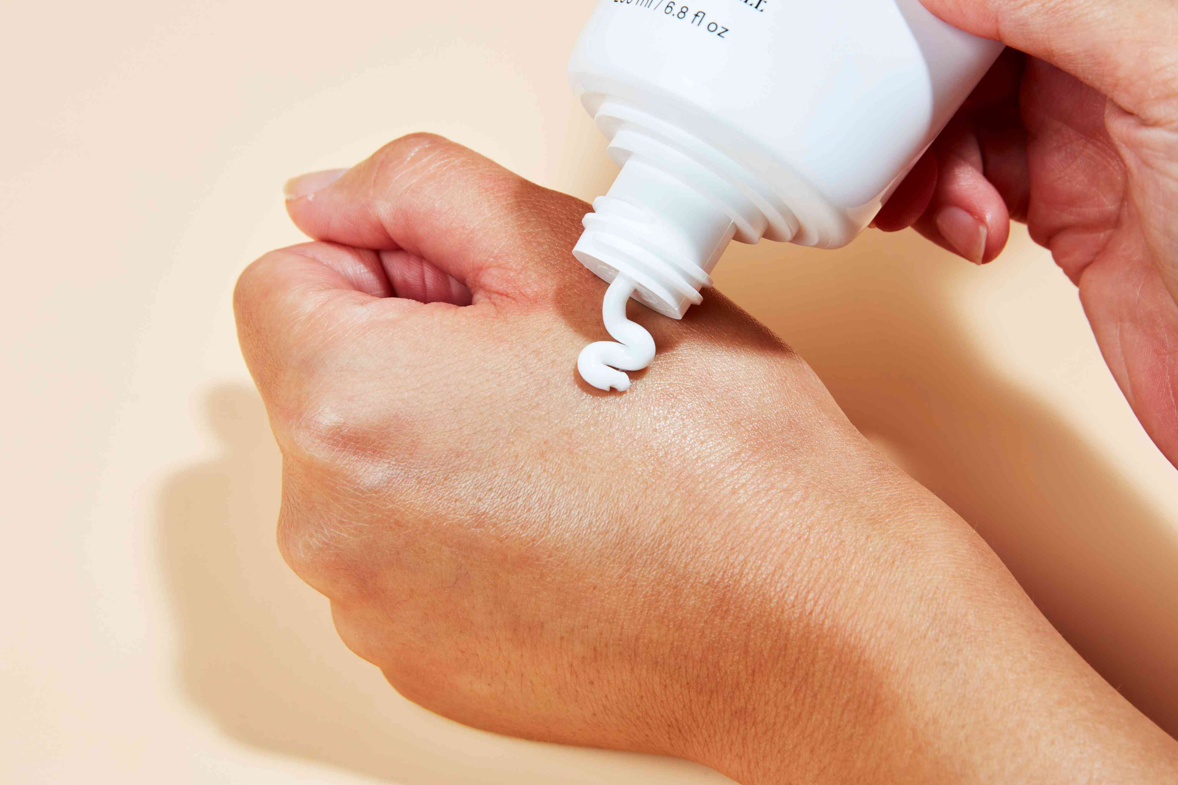 Closeup of hand dispensing Nécessaire The Body Lotion onto another hand