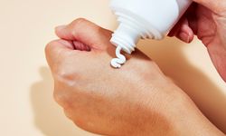 Closeup of hand dispensing Nécessaire The Body Lotion onto another hand