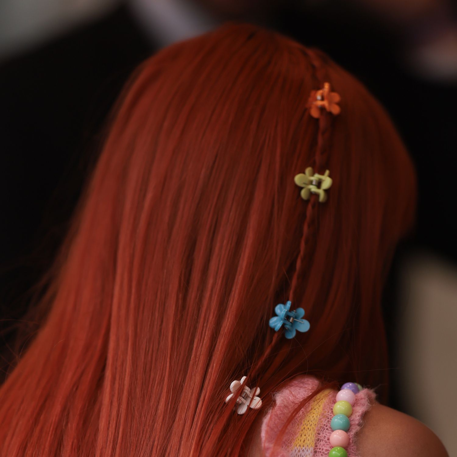 London Fashion Week guest wears a single micro braid in her red hair adorned with mini flower shaped claw clips