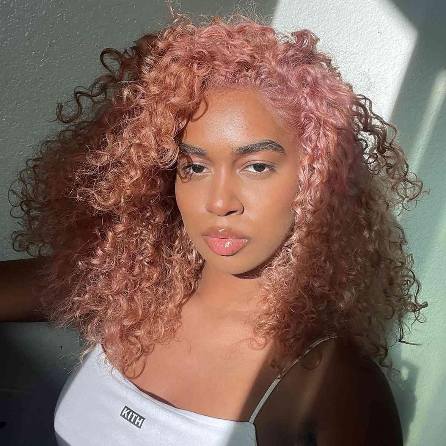 a woman with naturally textured hair in a rose gold color