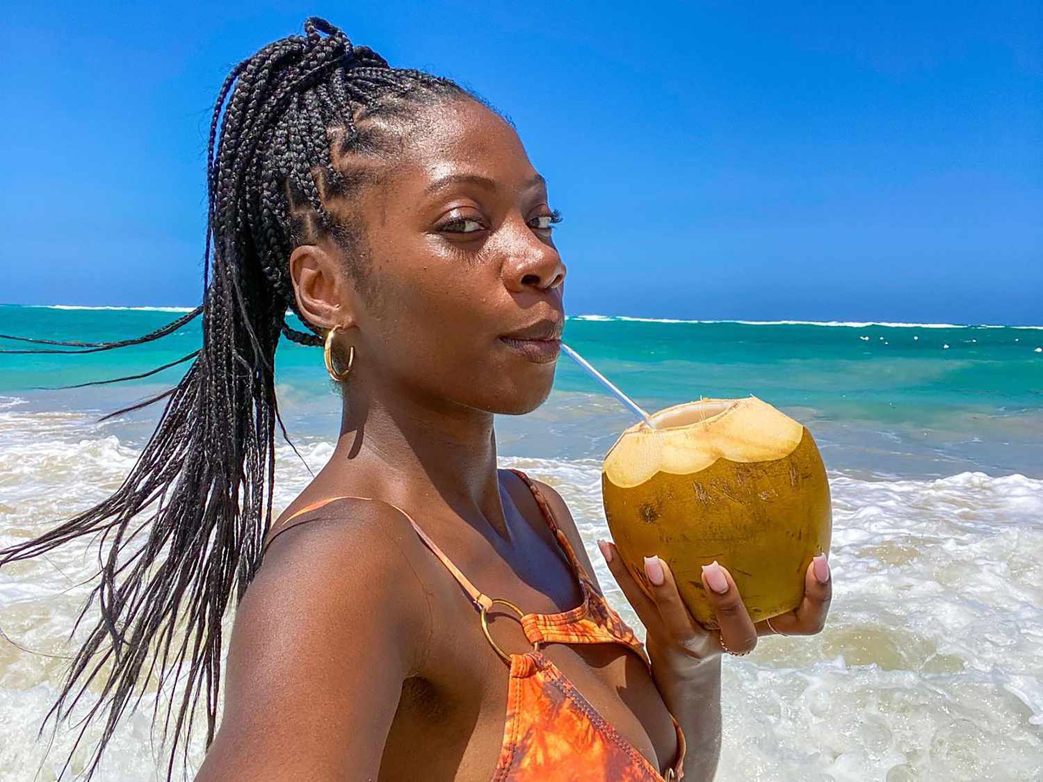 Byrdie social media editor Jasmine Phillips with braids in front of the ocean