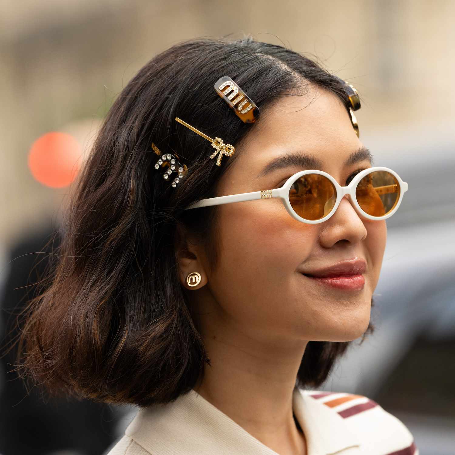 Proud Oranicha Krinchai wears stacked Miu Miu hair clips, earrings and sunglasses to the Miu Miu show at Paris Fashion Week